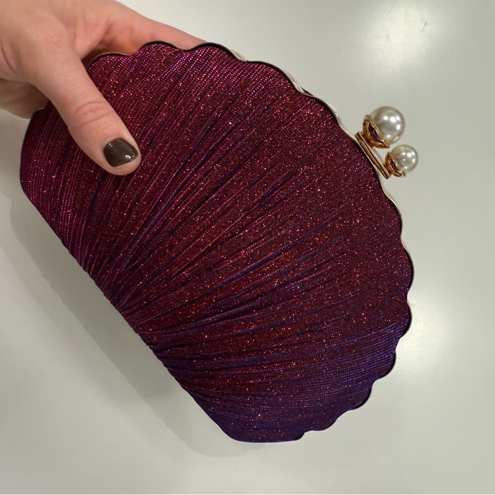 Sparkly wine red/plum colored shell clutch with pearl accented clasp.